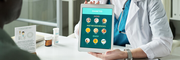 Middle aged Caucasian female doctor showing digital tablet with diabetes dietary recommendations to...