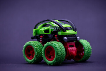 Childrens green monster truck toy on dark surface, suitable for kids playtime concept in advertising, education, and childrens publications.