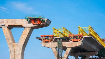Metal launching gantry on foundation of elevated expressway structure against blue sky background, Perspective side view