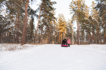 Father and daughter having fun with snow tube in the forest