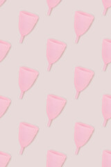 Pattern made of pink menstrual cup on a gray background.