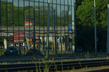 A train is traveling down the tracks that run in front of a large building featuring numerous...
