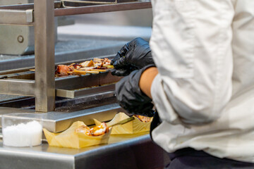Chef plating grilled vegan meat appetizers with black gloves on sustainable trays