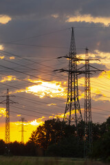 A beautiful sunset scene that features power lines prominently in the foreground, creating a...