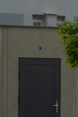 Fototapeta premium On the side of a building, there is a striking black door adorned with a decorative star, making it stand out against the structure