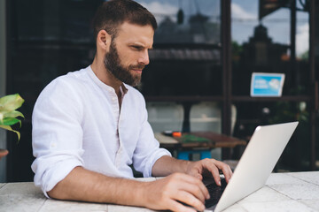 Remote worker focused intensely on laptop screen, seated at outdoor desk. Represents dedication and...
