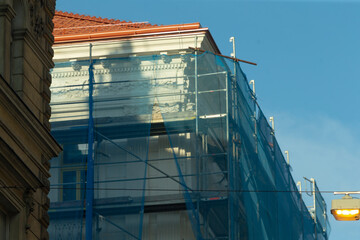 A large, towering building that has scaffolding prominently displayed on one side of it, showcasing...