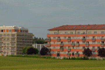 In the center of a vast open field, there stands a building that features a striking red roof,...