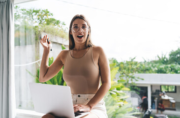 Surprised freelancer woman gestures with pen, expressing sudden idea or remote breakthrough while...