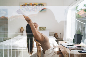 Stretching freelancer releases tension during digital routine, showing balance between productivity and tech-supported self-care in minimalist modern workflow.