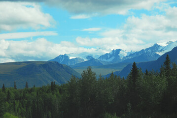 Alaska- Panoramic Landscape of Snow Capped Mountains and Forests During a Storm