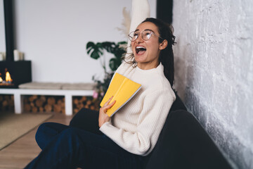 Young freelancer cheers with notebook in hand, celebrating breakthrough idea or success,...