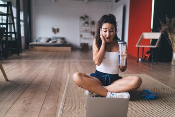 Sporty woman does bicycle crunch on floor, emphasizing abdominal strength and tech-assisted home...