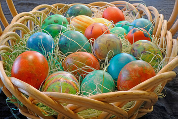 A wicker basket full of colorful eggs ready for Easter