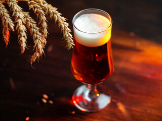 Beer glass on wooden table. Bright backlight