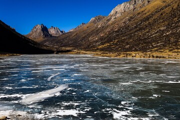 Frozen alpine lake surrounded by rugged peaks at Nyenpo Yutse Geological Park near Ngawa in the historical Amdo region, showcasing pristine Tibetan highland landscapes.