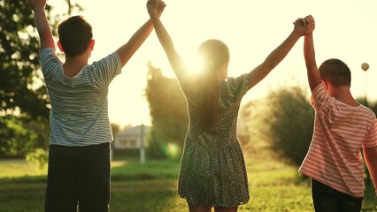 Boy and girl raise their hands. Friends together outdoors. Concept of success, kids victory. Children teamwork, group of children playing in park. Successful team of children winners. Family teamwork