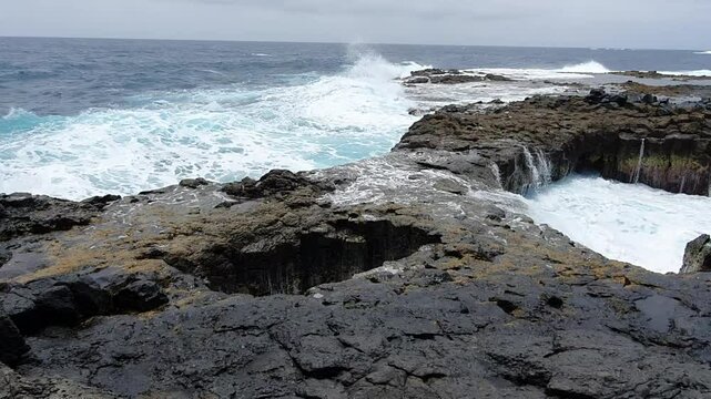Ocean waves crashing on volcanic rocks in buracona, sal island, cape verde