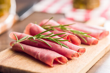 Sliced beef pastrami on cutting board on wooden table.