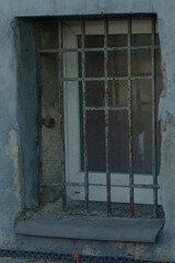 A window secured with iron bars on it and accompanied by a plain white door, creating a distinctive...