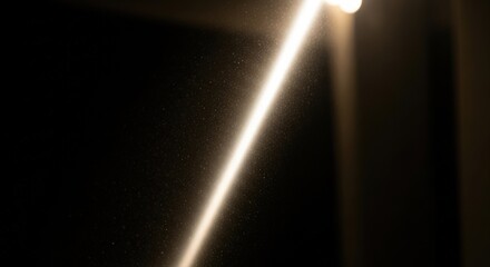 Bright light beam with floating dust particles on dark black background. Abstract atmospheric illumination for spiritual and funeral concepts.