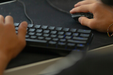 An individual is actively typing on a computer keyboard while simultaneously using a mouse for...