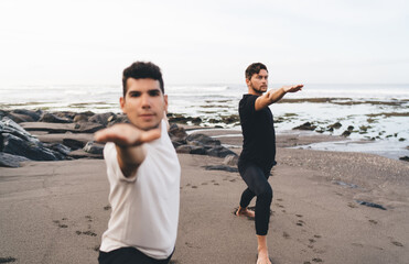 Yoga duo practices warrior II, arms extended with strong focus, capturing synchronized control,...
