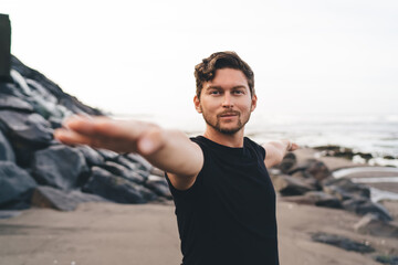 Portrait of man in warrior pose by sea, radiating confidence, breath awareness and masculine...