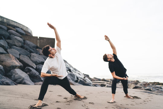 Two young adults holding yoga warrior pose in sync, symbolizing mental resilience, clarity, and intentional movement for today’s multitasking, screen-heavy tech environment.
