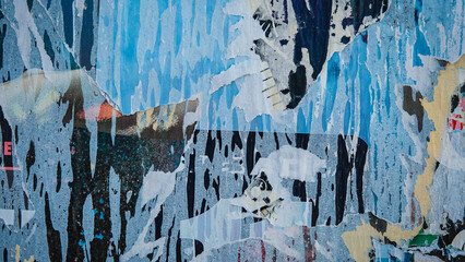 Old ripped torn posters texture background in city street, Blue, black, white colors