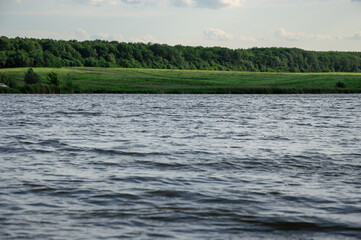 Gentle ripples create a serene atmosphere by the lake as the green forest outlines the horizon...