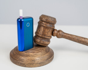 Judge's gavel and e-cigarette. Smoking ban. Tobacco heating systems. 