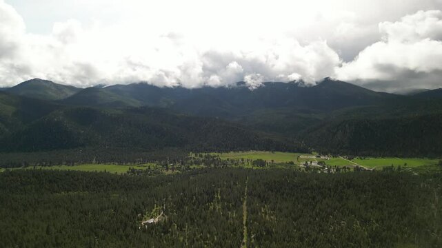 Aerial of Bitterroot Mountains and grassy meadows in Montana in spring with low clouds