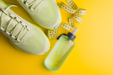 Sport running shoes and water bottle on yellow background. Top view.