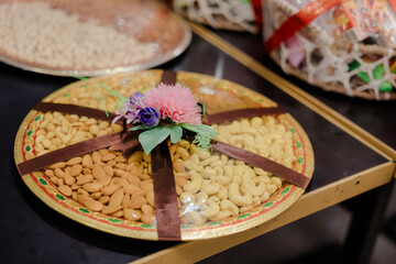 Decorative tray of mixed nuts, adorned with ribbon and flowers, ready for gifting. Festive presentation of edible treats. Celebration ready!