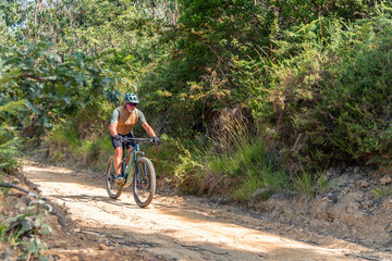 Obraz premium Senior cyclist enjoying electric mountain bike ride on sunny forest trail