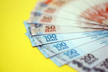 Close up of brazilian reais money bills in big amount on yellow. Pile of Brazil real currency