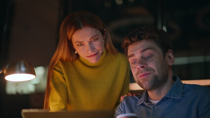 Late workers discussing project looking laptop screen at night office closeup. 