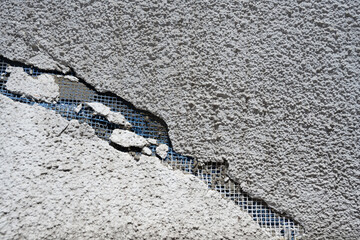 Cracked Plaster with Exposed Mesh on a Wall