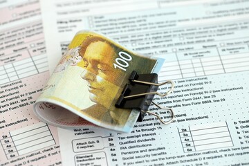 Israel New Shekels banknotes on tax form blank. The current Israel money bills lies on tax report