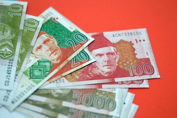 Pakistan rupees banknotes on red background. The current Pakistan money bills