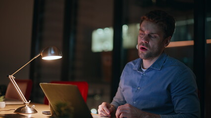 Frustrated freelancer working late evening failing project in apartment closeup.