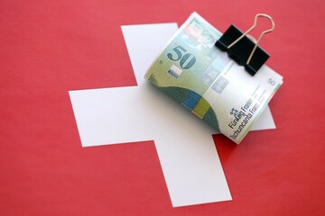 Swiss franc banknotes and flag. The francs money bills lies on flag in big amount