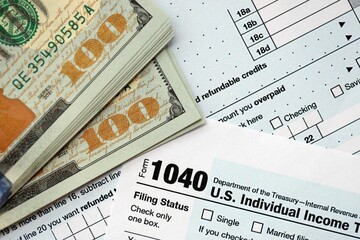 Hundred dollar bills and 1040 individual income tax return form blank close up