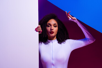 Trendy woman in a white bodysuit posing with vibrant neon lighting and modern artistic elements
