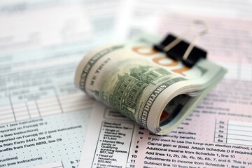 Big amount of United States hundred dollar bills in bunch on table with tax return form