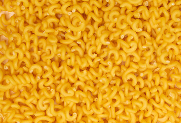Raw yellow cavatappi pasta texture background top view. Pile of dry uncooked noodles pattern