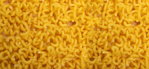 Raw yellow cavatappi pasta texture background top view. Pile of dry uncooked noodles pattern