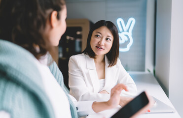 Fototapeta premium Focused female professional thinking over notes, leaning forward in chair. Smart outfit, modern workspace around her. Subtle emotion in quiet moment