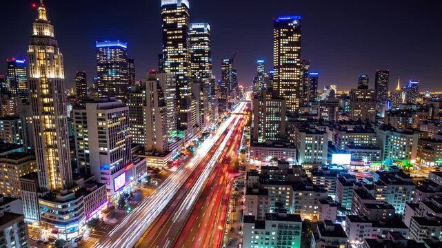 Vibrant night cityscape with illuminated skyscrapers and light trails from traffic in a modern urban downtown.